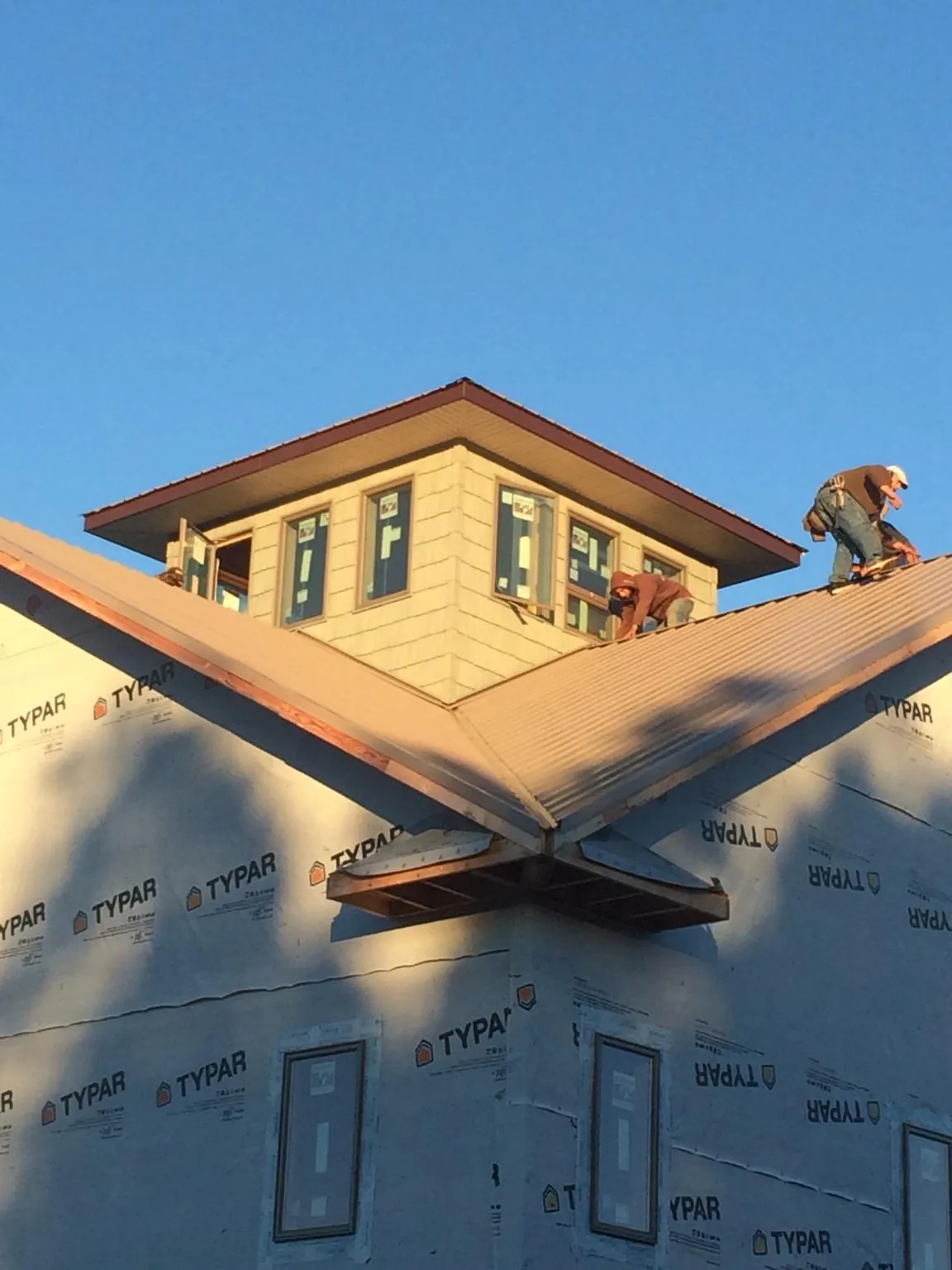 Roofers working around a rooftop cupola on a new metal roof at sunset — Roof Waterproofing in Mount Vernon by Roofing Brothers